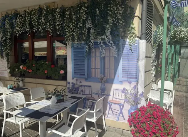 Stoliki przed wejściem, wśród pelargonii